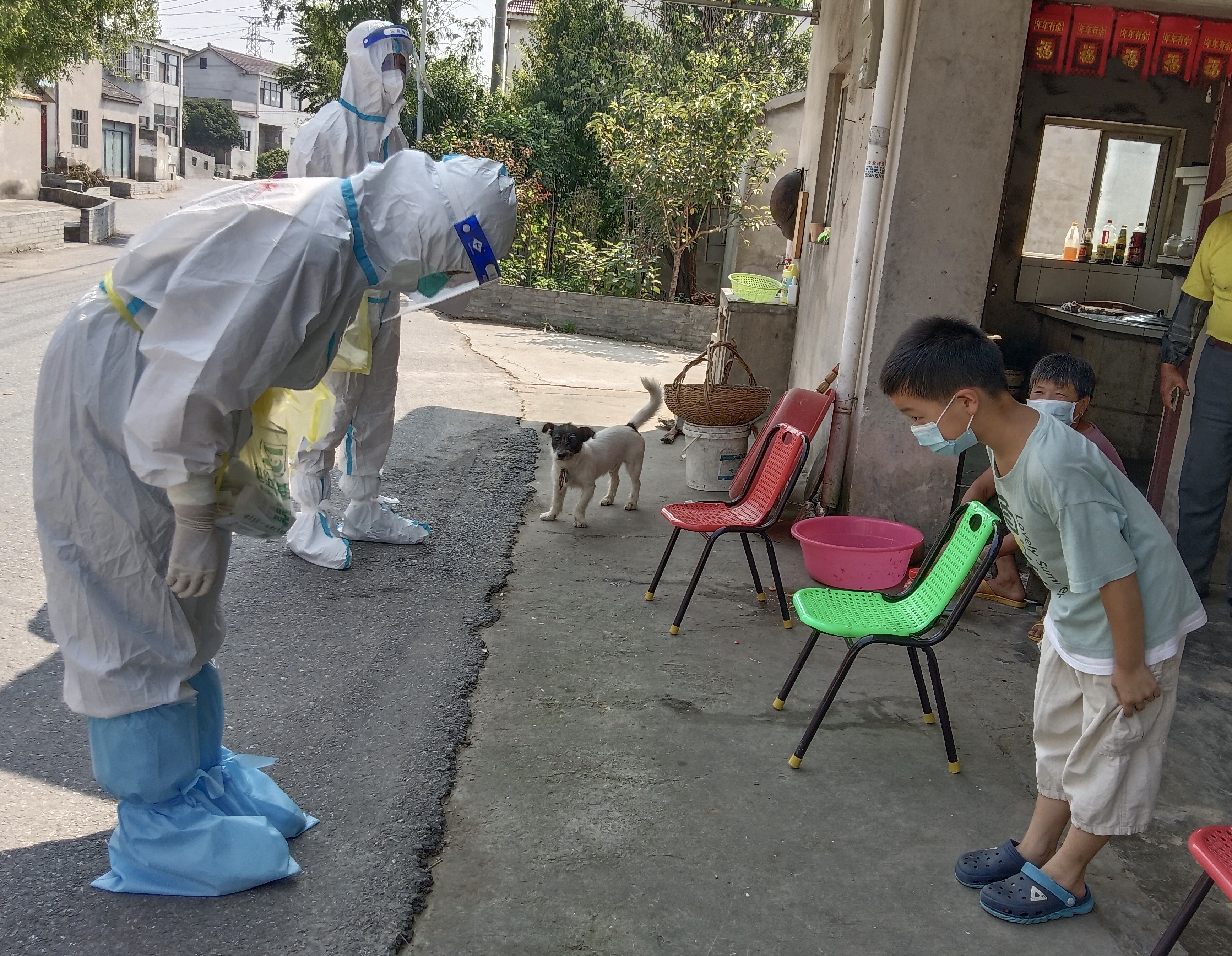 8月1日中午,禄口街道陈巷社区倪家村,盐城响水前来支援南京抗疫的护士葛佳佳为王宇新小朋友采集咽拭子后,王宇新向葛佳佳深深一鞠躬致谢,葛佳佳也躬身回礼。